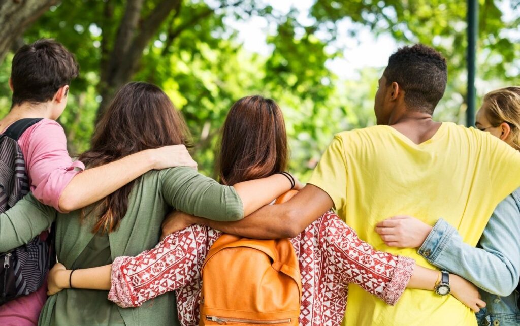People's linking arms in a forest; showing their backs